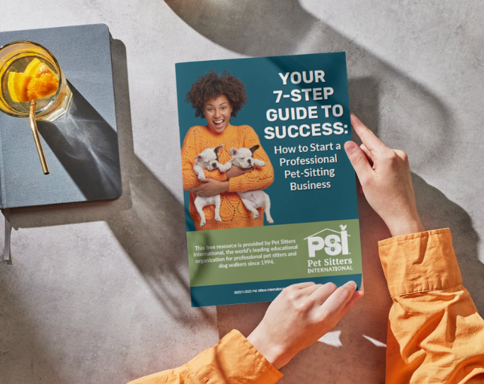 How to start a pet sitting business Hands of person holding a book with the title Your 7-Step Guide to Success, How to Start a Professional Pet-Sitting Business